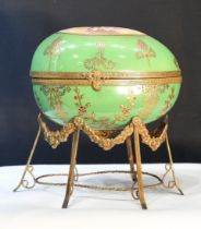 A painted porcelain egg on metal brass-coloured stand