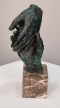 Bronze casting of hands with a verdigris finish on solid marble base