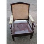 A 19th century Carters mahogany and cane back commode chair, with hinged drop down arms, having a