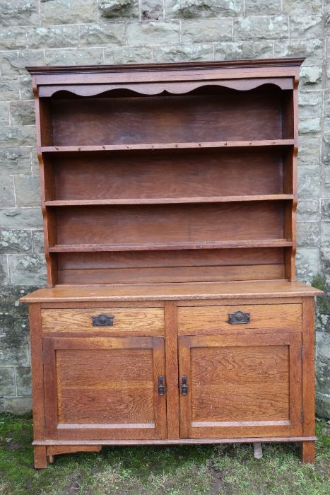 An Arts and Crafts oak sideboard, with graduated shelves, over two drawers, with cupboards below,