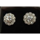 A pair of diamond set daisy head cluster earrings, set with a central diamond surrounded by a