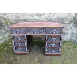 An Antique oak pedestal desk, the drawer front carved with mask handles, fitted with nine drawers