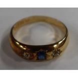 A Victorian 18ct yellow gold ring, gypsy set with an oval-cut sapphire and two old cut diamonds,
