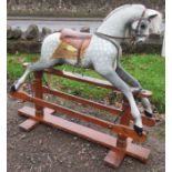 A large rocking horse, painted dapple grey, on a pine base