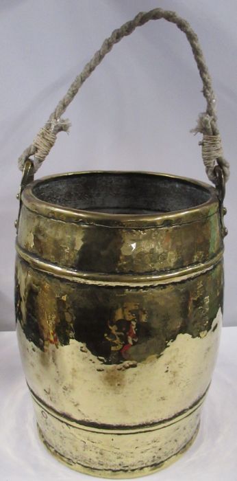 An Arts and Crafts hammered brass barrel shaped ash bucket, with rope handle