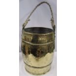 An Arts and Crafts hammered brass barrel shaped ash bucket, with rope handle