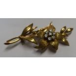 An 18ct gold leaf brooch, set with a flower head of seven diamonds, weight 9.3g
