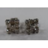 A pair of 18k white gold diamond cluster earrings, each with central princess-cut diamond with