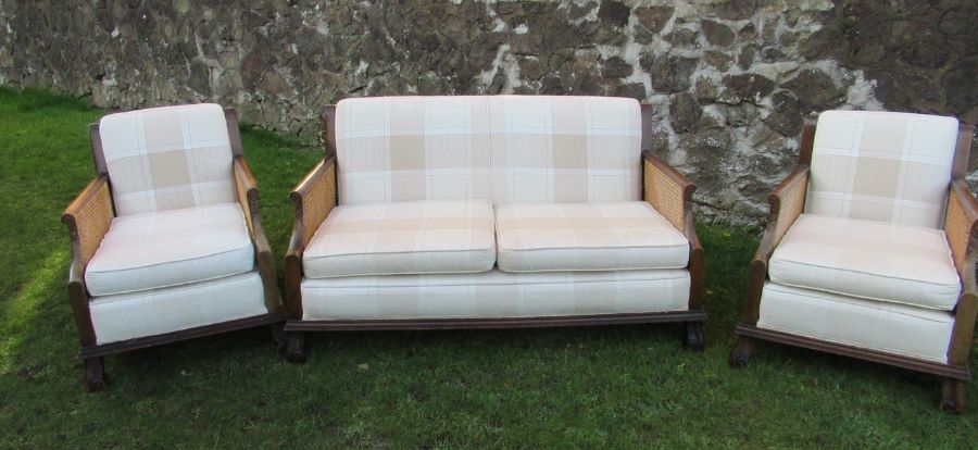 A three piece bergere suite, comprising a two seater settee and a pair of armchairs, with cane sides