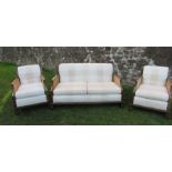 A three piece bergere suite, comprising a two seater settee and a pair of armchairs, with cane sides
