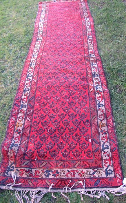 An Eastern design runner, with repeating symbols to the red ground, 137ins, x 38ins