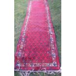 An Eastern design runner, with repeating symbols to the red ground, 137ins, x 38ins