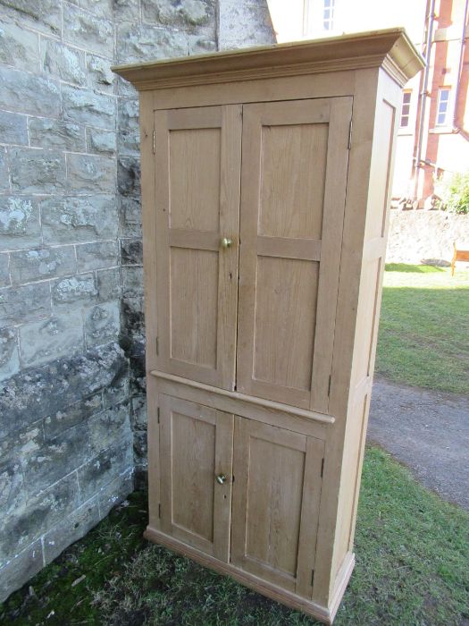 A pine double cupboard, having two pairs of fielded cupboard doors opening to reveal adjustable