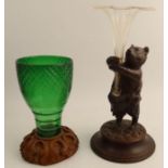 A carved Black Forest wooden model, of a standing bear, holding a glass trumpet shaped vase,