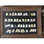 A collection of china thimbles, to include Royal Worcester examples, some signed, in a display case