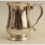 A Georgian silver pint mug, with embossed decoration and engraved with a crest and initials,