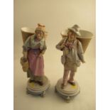 A pair of 19th century continental figures of a man and a lady with baskets,  raised on circular