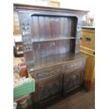 An antique style oak dresser the upper section with carved figures width 46ins height 67"