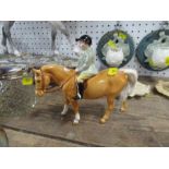 A Beswick model, of a child in green jacket riding a palomino pony - there is a minor chip to cap