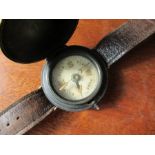 A World War Two wrist compass, with black metal hunter style case, on a leather strap
