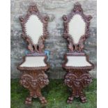 A pair of Continental carved hall chairs, with upholstered panel to the back and seat, decorated
