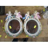 A pair of Meissen porcelain framed wall mirrors, decorated with cherubs and swags, af, overall