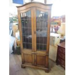 An oak cabinet, with a pair of leaded glazed doors over a cupboard, height 78ins, width 34ins, depth