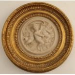 A 20th century relief parian circular plaque, decorated with putti, in a gilt frame, overall