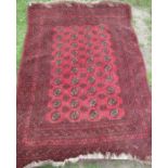 An Eastern design red ground rug, decorated with repeating symbols and a multi band border, 60ins