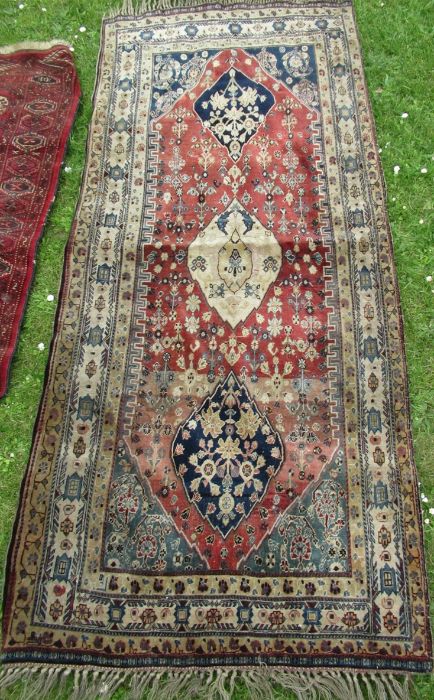 An Eastern design rug, the red ground field decorated with flowers, 36ins x 79ins