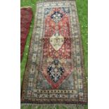 An Eastern design rug, the red ground field decorated with flowers, 36ins x 79ins