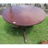 A mahogany circular dining table, raised on a central carved column with three outswept supports,