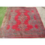 An Eastern design red ground rug, decorated with repeating symbols, 84ins x 84ins