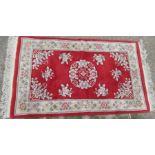 A red ground wool wash rug, decorated with flowers, 66ins x 36ins