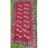 A red ground rug, the field decorated with 16 repeating lozenges, 36ins x 70ins