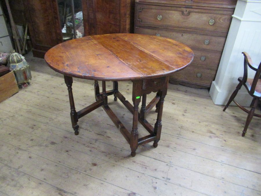 An 18th century yew wood gate leg table, raised on turn baluster legs, 45ins x 39ins, height 29ins