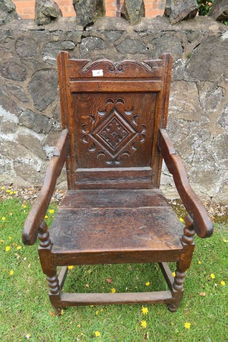 An antique oak Wainscote chair with the back panel having carved decoration.