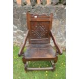 An antique oak Wainscote chair with the back panel having carved decoration.