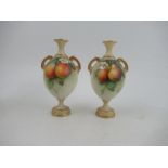 A pair of Royal Worcester pedestal vases, decorated with fruit by F Parker, with blush ivory neck,