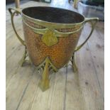 An Arts and Crafts style beaten copper jardiniere, with brass handles, mounts and legs, height 10ins