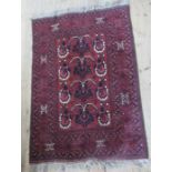 An Eastern design rug, the burgundy ground with repeating symbols, 58ins x 40ins