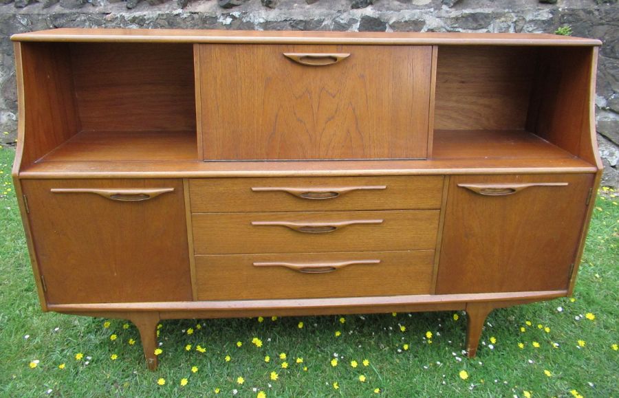 A Retro sideboard, with front flap drinks cabinet, flanked by cupboards with sliding glass doors,