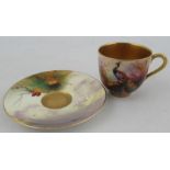 A Royal Worcester miniature coffee cup and saucer, the cup and saucer decorated with a peacock and