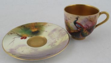 A Royal Worcester miniature coffee cup and saucer, the cup and saucer decorated with a peacock and