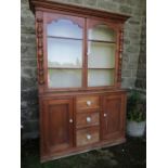 A pine cupboard the upper section having two glazed doors over cupboards and drawers to the base  (