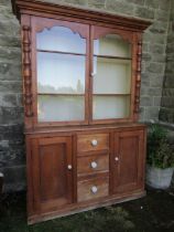 A pine cupboard the upper section having two glazed doors over cupboards and drawers to the base  (