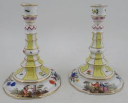 A pair of Continental porcelain candlesticks, decorated with figures and flowers, with bands of