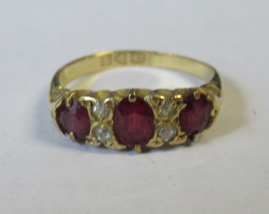 An 18ct three stone ruby ring, set with diamonds between the rubies, weight 2.9g