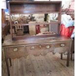An Antique oak dresser base, with associated rack back, the base fitted with three drawers, rack