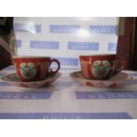 Two Oriental porcelain tea cups and saucers, decorated with panels to the a red ground, with